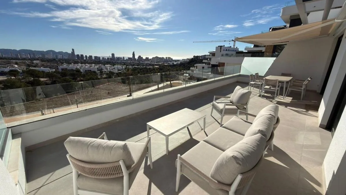 Nameštena terasa sa staklenom ogradom i pogledom na grad