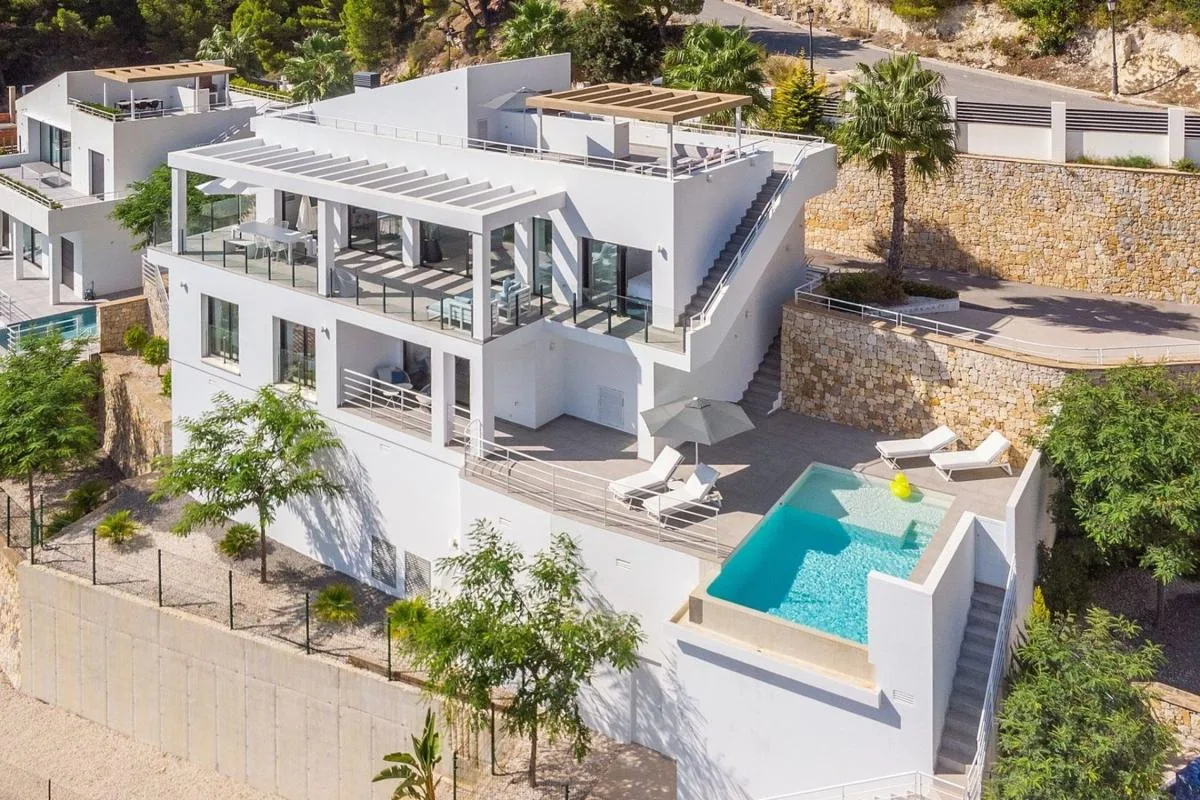 Vista aérea de la villa blanca con terrazas y piscina